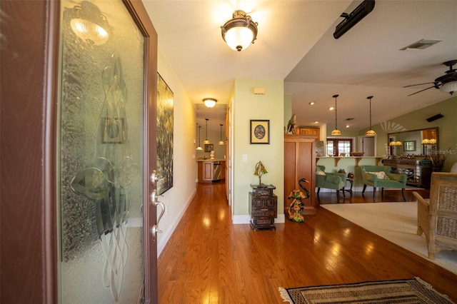 corridor featuring light wood-type flooring and vaulted ceiling