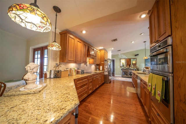 kitchen featuring dark wood-type flooring, stainless steel appliances, tasteful backsplash, light stone counters, and pendant lighting