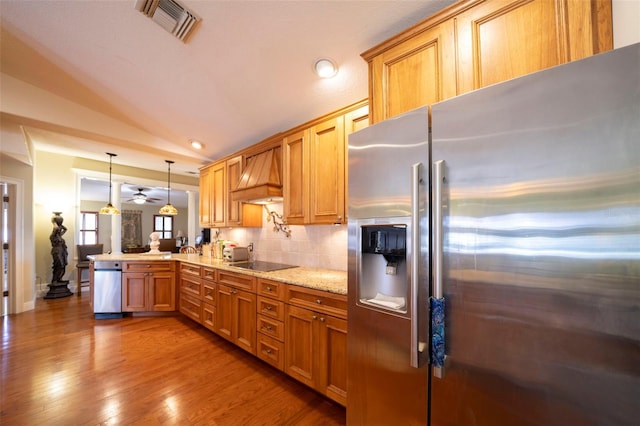 kitchen featuring kitchen peninsula, stainless steel fridge, lofted ceiling, decorative light fixtures, and black electric stovetop