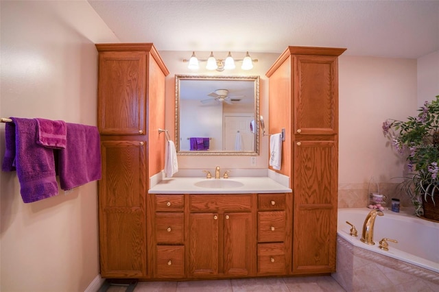 bathroom with tile patterned floors, vanity, ceiling fan, and a relaxing tiled tub