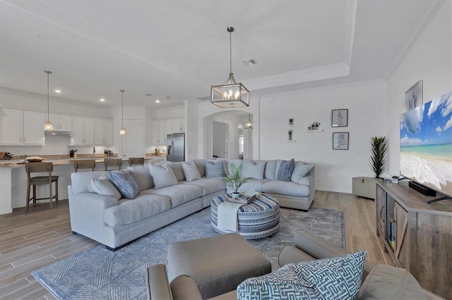 living room with crown molding, a notable chandelier, and light wood-type flooring