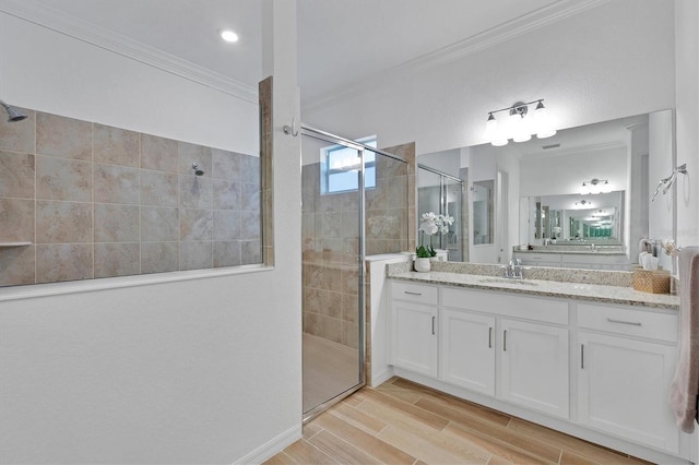 bathroom with a shower with door, vanity, and ornamental molding