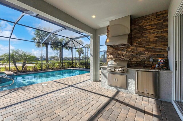 view of swimming pool with area for grilling, a patio area, glass enclosure, and an outdoor kitchen