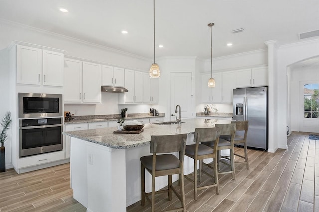 kitchen with white cabinetry, a center island with sink, sink, and appliances with stainless steel finishes