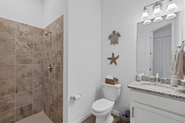 bathroom featuring a tile shower, vanity, and toilet