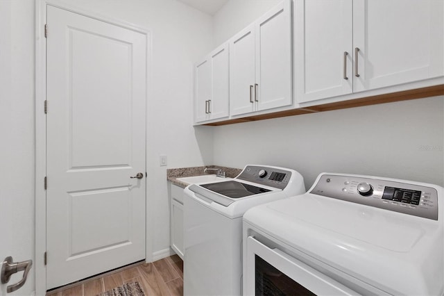 laundry area featuring washing machine and clothes dryer, sink, and cabinets