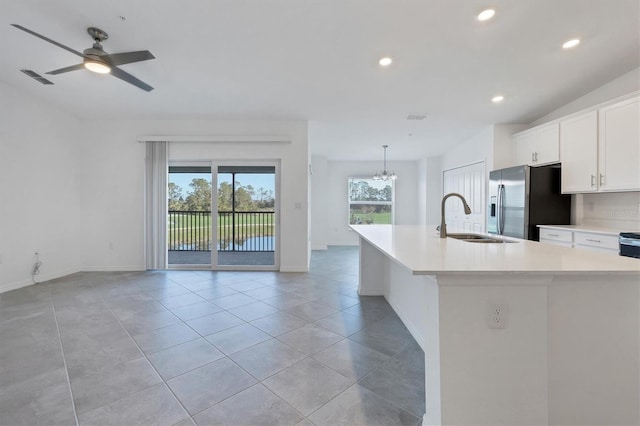 12470 Wellen Golf St Unit 203, Venice, FL 34293 - kitchen with light tile patterned flooring, an island with sink, sink, white cabinets, and stainless steel fridge