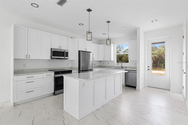 kitchen with light stone countertops, appliances with stainless steel finishes, sink, a center island, and white cabinetry