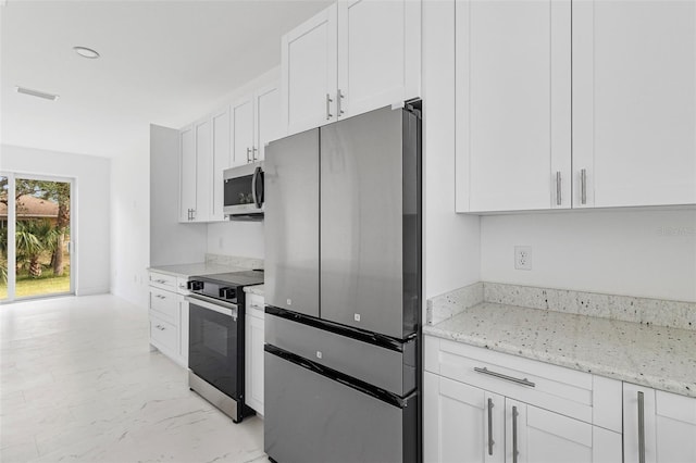 kitchen featuring white cabinetry, light stone countertops, and appliances with stainless steel finishes