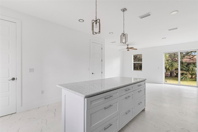 kitchen featuring decorative light fixtures, a center island, light stone countertops, and ceiling fan