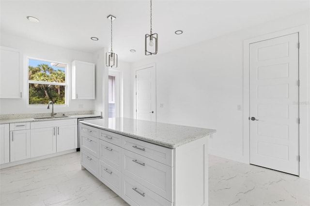 kitchen with sink, hanging light fixtures, a kitchen island, light stone counters, and white cabinetry