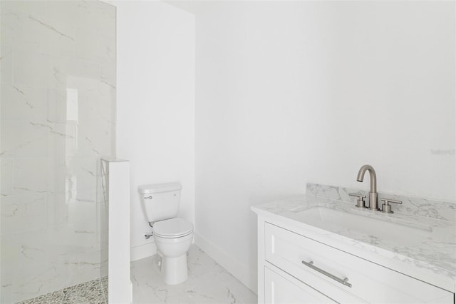 bathroom with tiled shower, vanity, and toilet