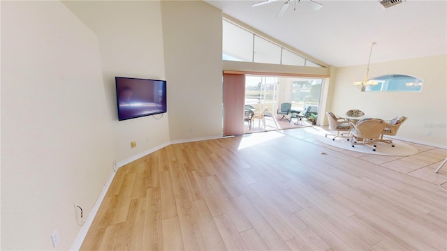 unfurnished living room with light hardwood / wood-style flooring, high vaulted ceiling, and ceiling fan with notable chandelier