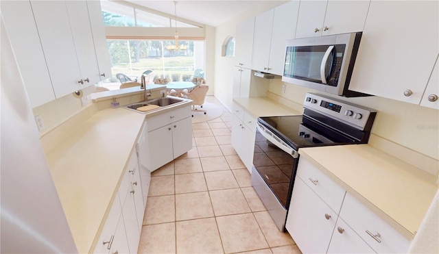 kitchen with sink, a chandelier, vaulted ceiling, white cabinets, and appliances with stainless steel finishes