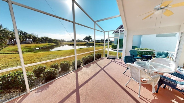 sunroom featuring ceiling fan and a water view