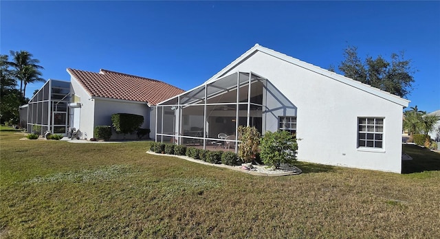 rear view of property featuring a yard and glass enclosure