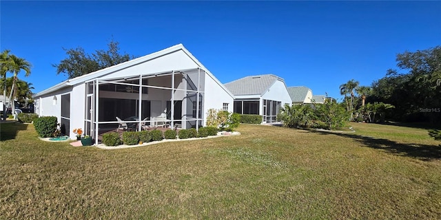 back of property featuring glass enclosure and a yard