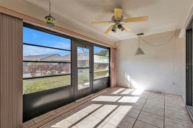 unfurnished sunroom featuring ceiling fan and plenty of natural light