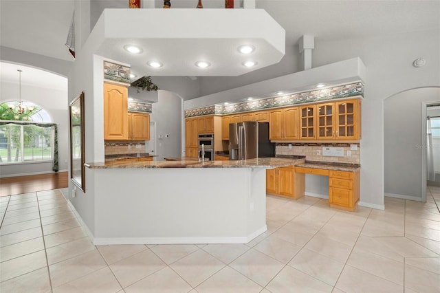 kitchen featuring high vaulted ceiling, light tile patterned floors, decorative backsplash, and appliances with stainless steel finishes