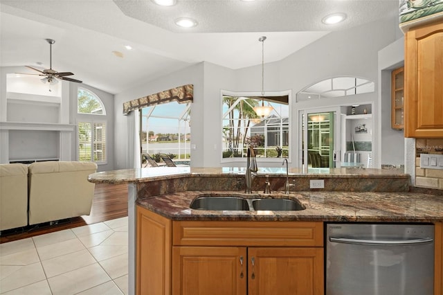 kitchen with dark stone counters, ceiling fan, sink, dishwasher, and lofted ceiling