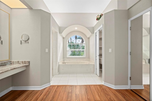 bathroom with hardwood / wood-style flooring, toilet, lofted ceiling, and a bath