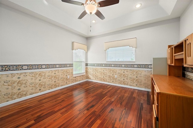 unfurnished room with a tray ceiling, ceiling fan, and dark hardwood / wood-style flooring