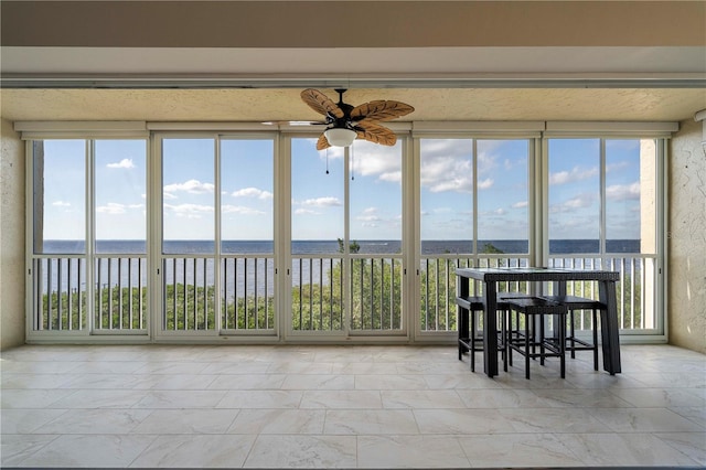 sunroom / solarium featuring ceiling fan and a water view