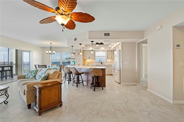 living room with ceiling fan with notable chandelier and sink