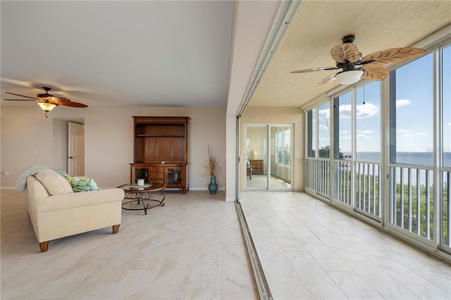 sunroom / solarium featuring ceiling fan and a water view