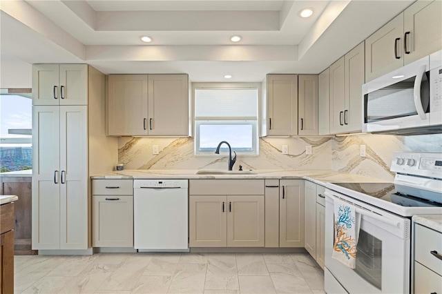 kitchen featuring backsplash, sink, white appliances, and a tray ceiling