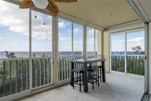 sunroom featuring a water view and ceiling fan