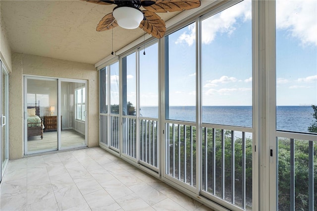 unfurnished sunroom featuring a water view and ceiling fan