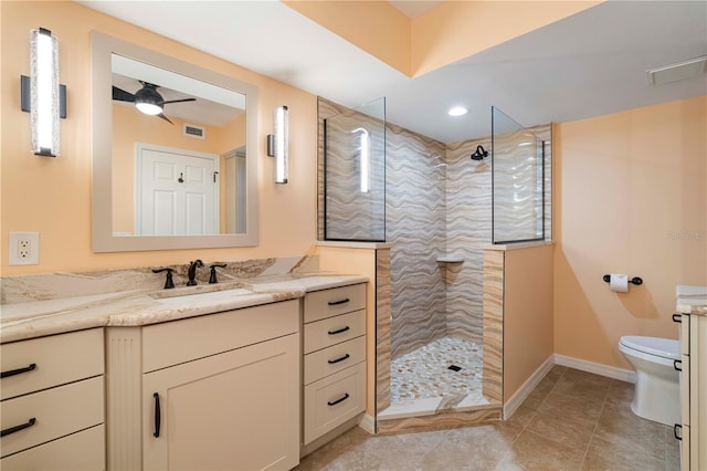 bathroom featuring ceiling fan, toilet, vanity, and a tile shower