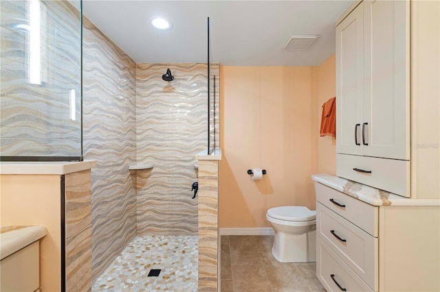 bathroom featuring tile patterned floors, toilet, and a tile shower