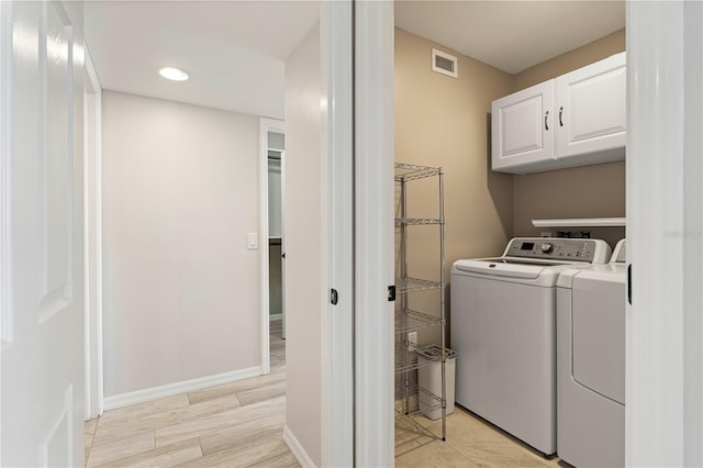 laundry room featuring cabinets, washer and dryer, and light hardwood / wood-style floors