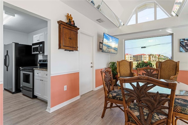 kitchen with light wood-type flooring, appliances with stainless steel finishes, and white cabinets