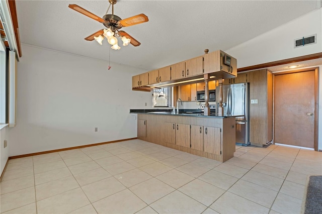 kitchen featuring ceiling fan, kitchen peninsula, stainless steel fridge, vaulted ceiling, and light tile patterned floors