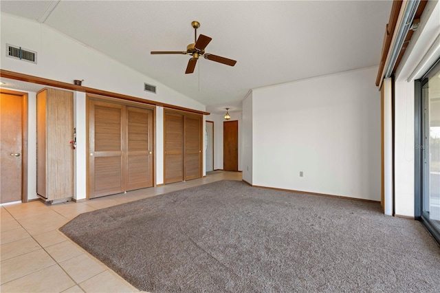 unfurnished bedroom featuring light tile patterned floors, two closets, ceiling fan, and lofted ceiling