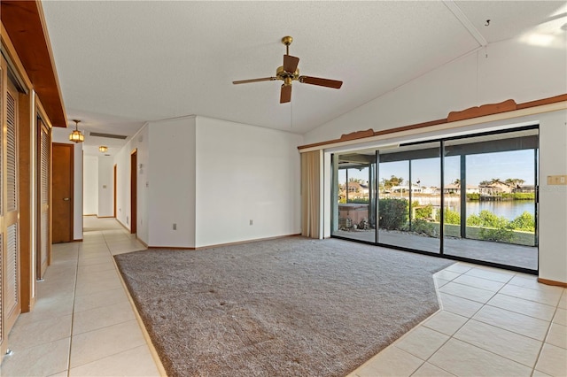 spare room with ceiling fan, a water view, light tile patterned floors, and vaulted ceiling