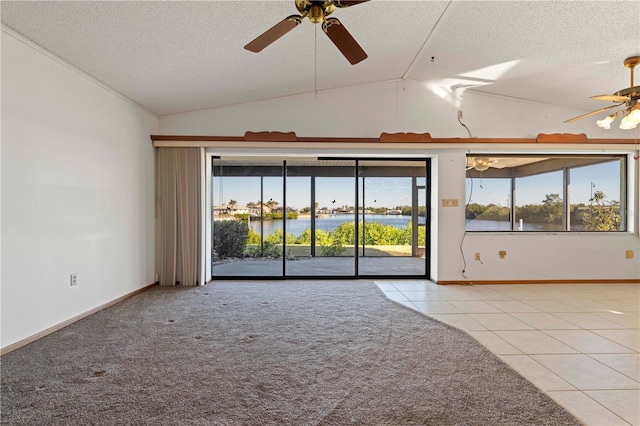 tiled empty room featuring a textured ceiling, a water view, vaulted ceiling, and ceiling fan