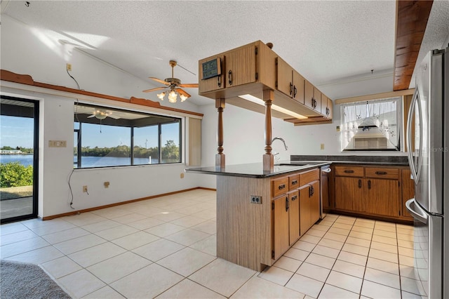 kitchen featuring sink, kitchen peninsula, lofted ceiling, a water view, and appliances with stainless steel finishes