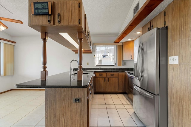 kitchen with a breakfast bar, a textured ceiling, light tile patterned flooring, kitchen peninsula, and stainless steel appliances