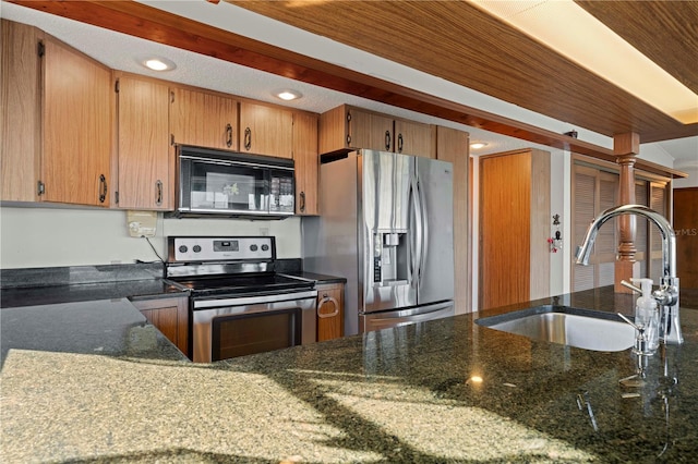 kitchen with stainless steel appliances, dark stone countertops, and sink