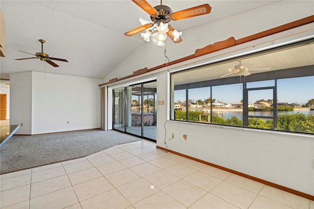 tiled spare room featuring plenty of natural light, ceiling fan, a water view, and vaulted ceiling