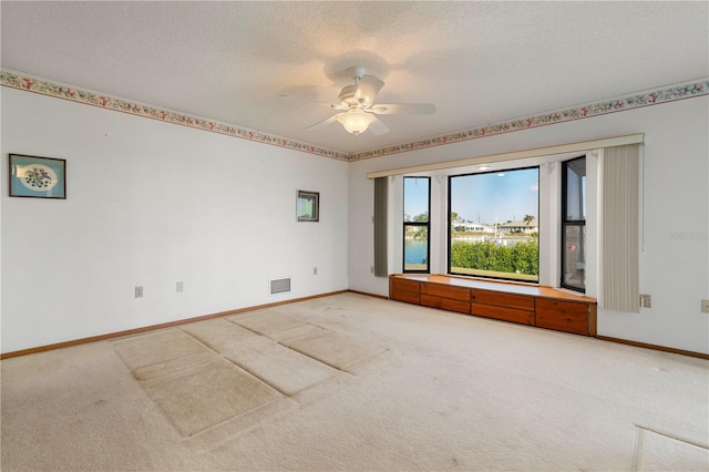 carpeted spare room with ceiling fan and a textured ceiling