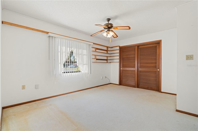 unfurnished bedroom with ceiling fan, light colored carpet, a textured ceiling, and a closet