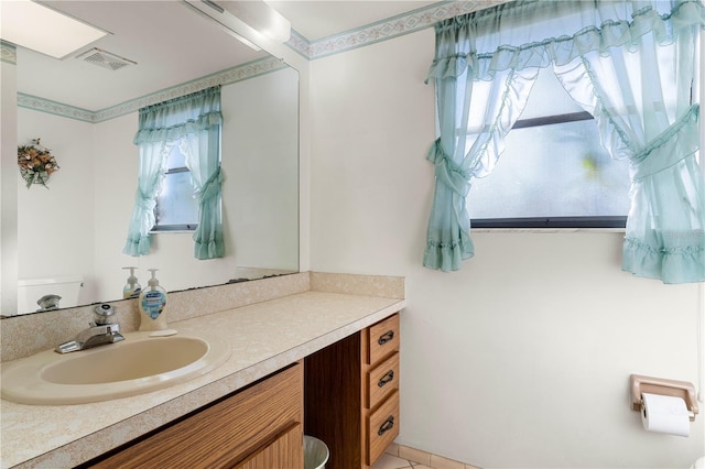 bathroom with vanity, a healthy amount of sunlight, and toilet