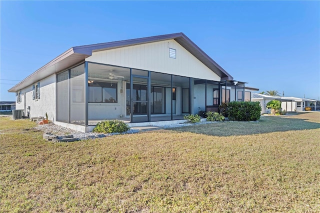 rear view of property featuring a sunroom, ceiling fan, a yard, and central AC