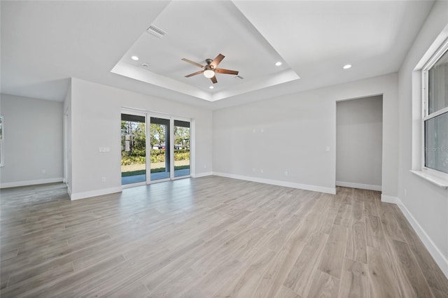 interior space featuring ceiling fan, light hardwood / wood-style floors, and a raised ceiling