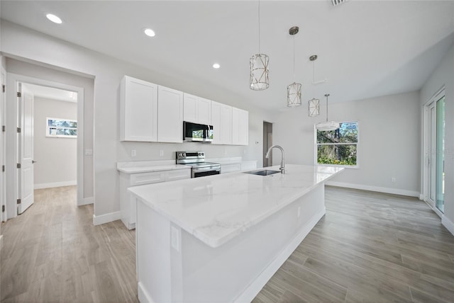 kitchen with white cabinets, decorative light fixtures, stainless steel appliances, and an island with sink